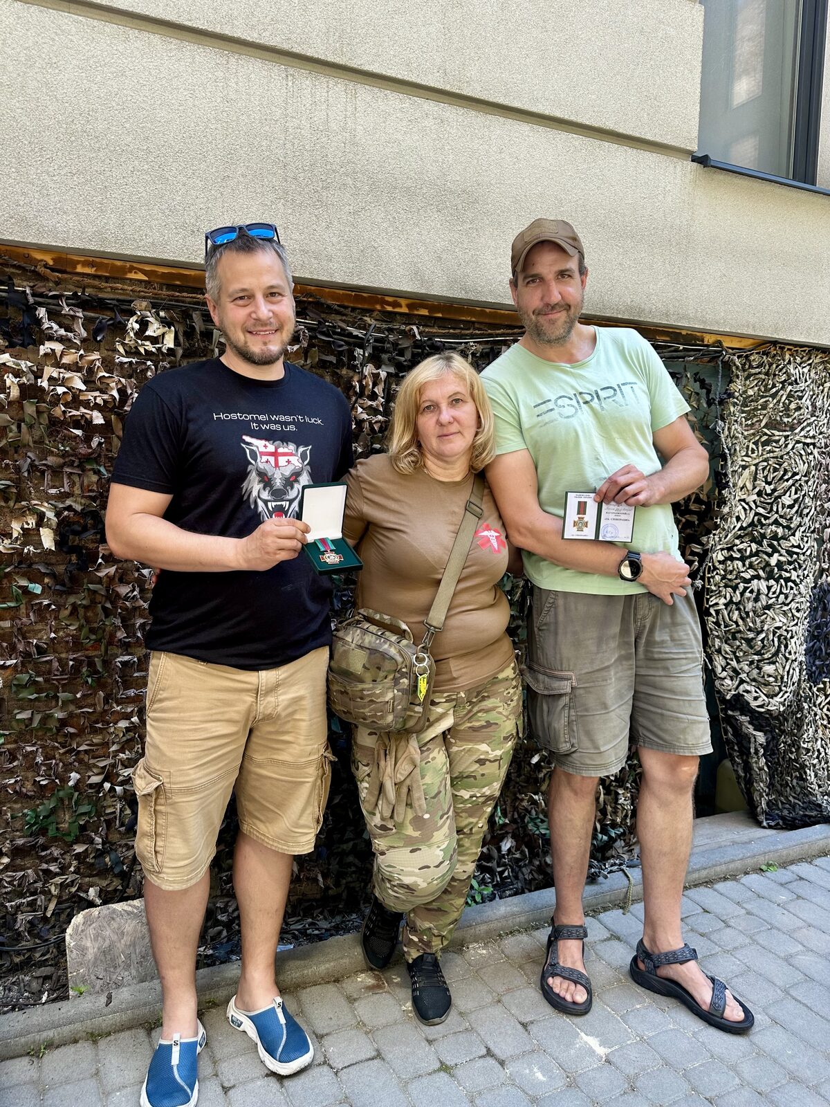 Nataša odovzdáva medailu 5. slobožanskej brigády Sklárčikovi a Forróovi, tričko s nápisom Hostomel wasn't luck. It was us.